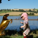 child with golden horse balloon beside a river