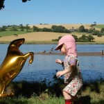 child with golden horse balloon beside a river